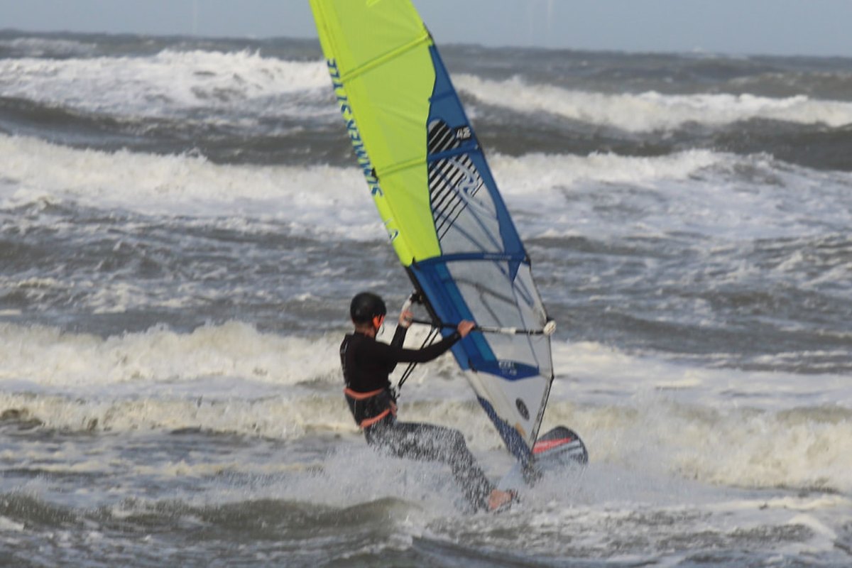 Windsurfer riding across open blue water