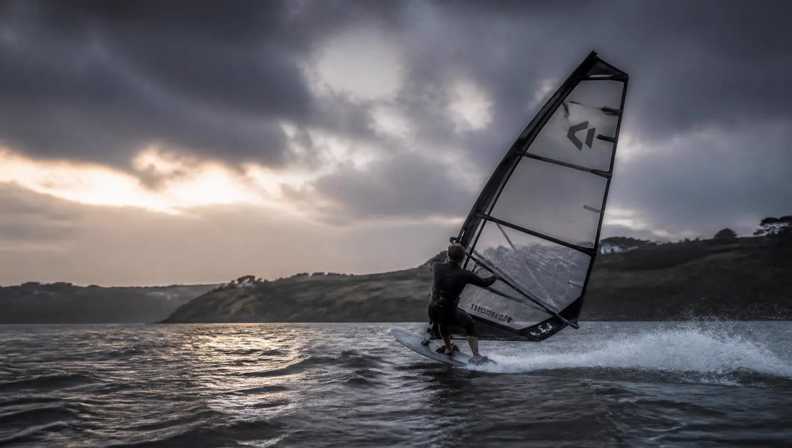 Windsurfer crossing blue-grey coastal water